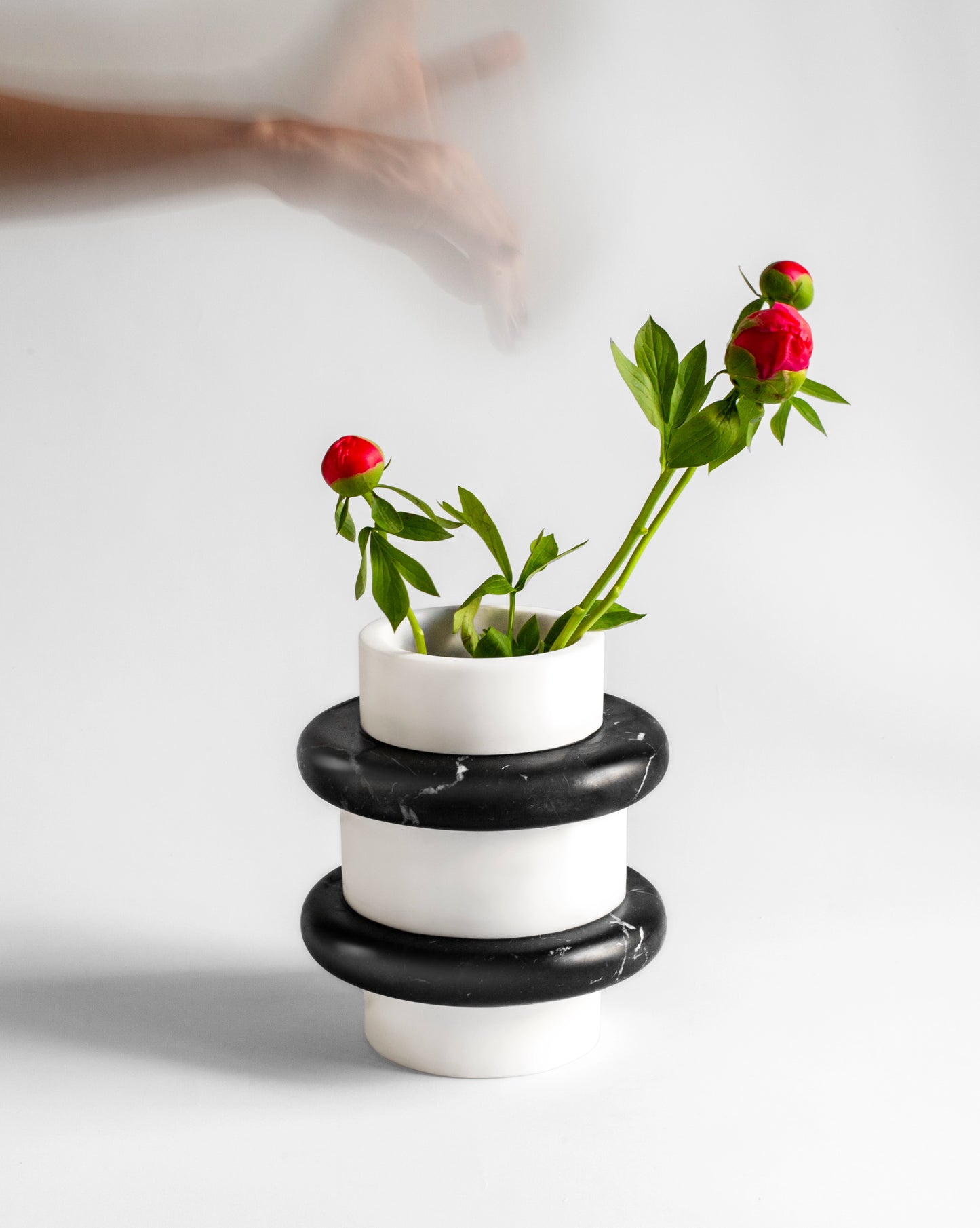 Lumière vase combining Nero Marquina and white Thassos marble with red peony flowers and moving hand