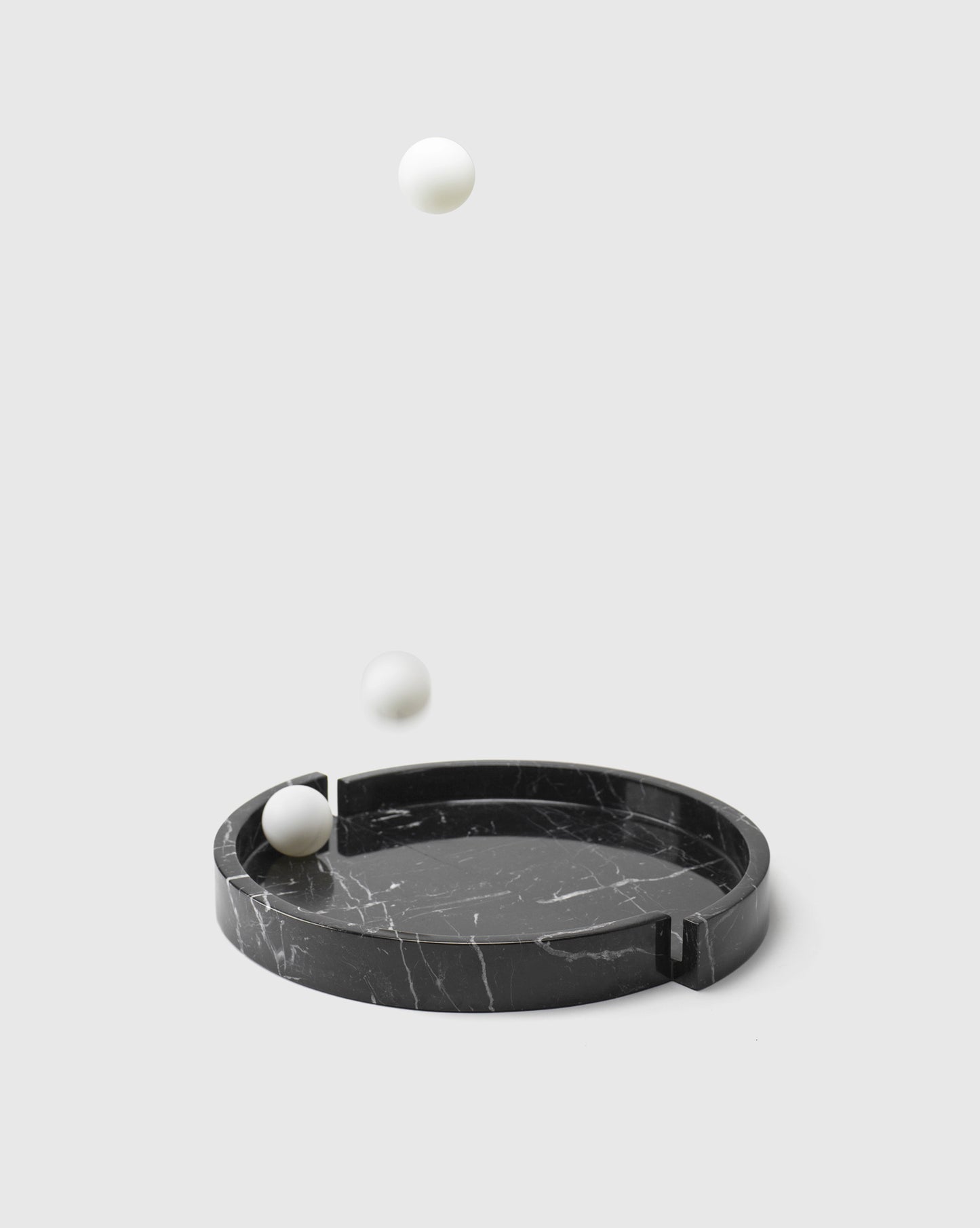 Still life of the Modern home decor featuring the black "Mistake" tray crafted from premium Nero Marquina marble with pingpong balls, highlighting its distinct and playful design.