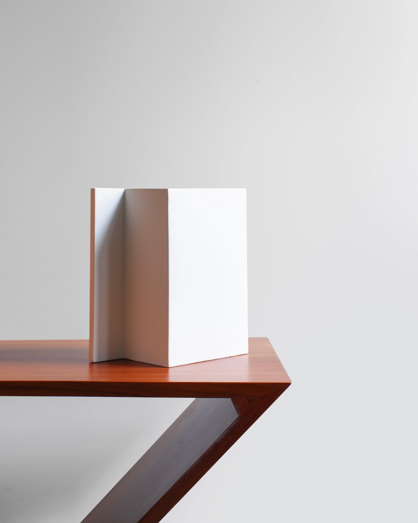 Minimalist matte white Rook Vase, showcasing an elegant design on a Rietveld wood chair, still life.