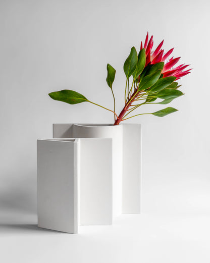 Modern matte white Rook Vase designed by artist Sara Khamisi with pink flower