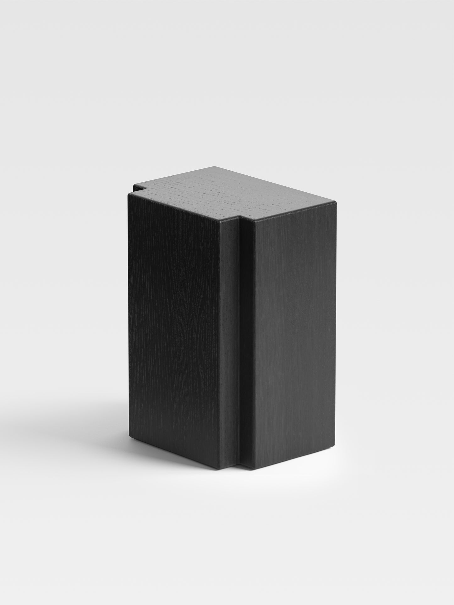 Angled view of Lui black oak side table showing its monolithic form, minimalist geometry, and artistic Milanese craftsmanship.